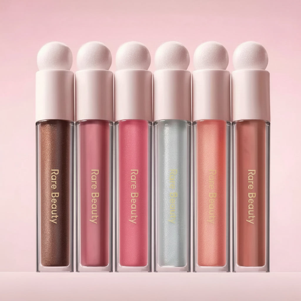 Set of six lip glosses from Rare Beauty on a pink background